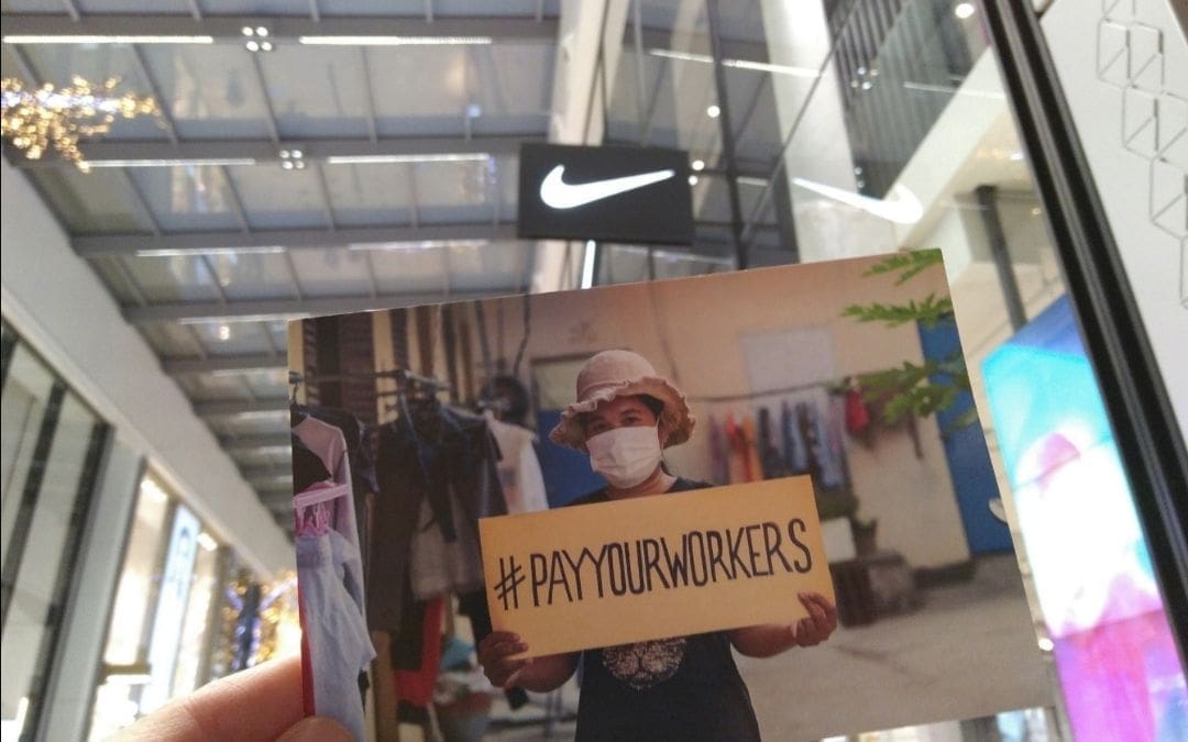 Cartel de la campaña Pay Your Workers ante una tienda de NIKE